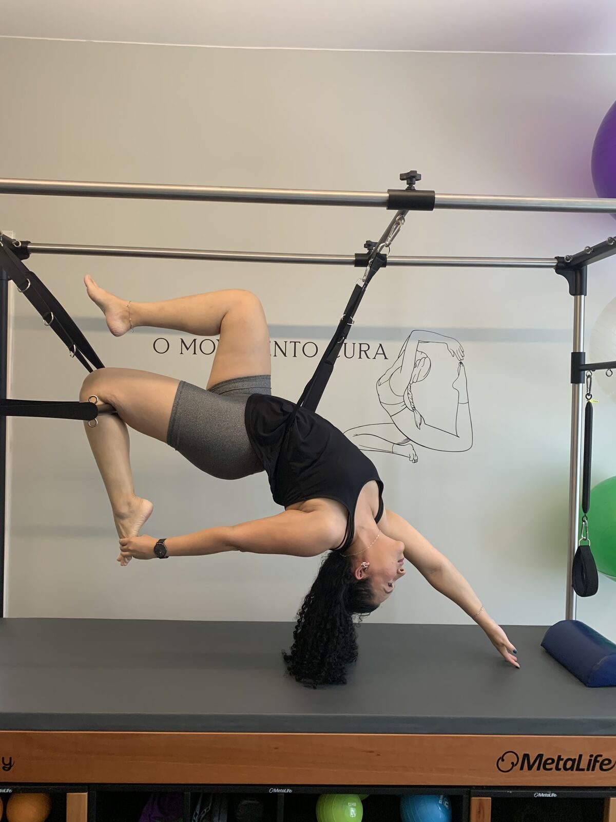 Aluna realizando exercício de extensão no Cadillac de pilates