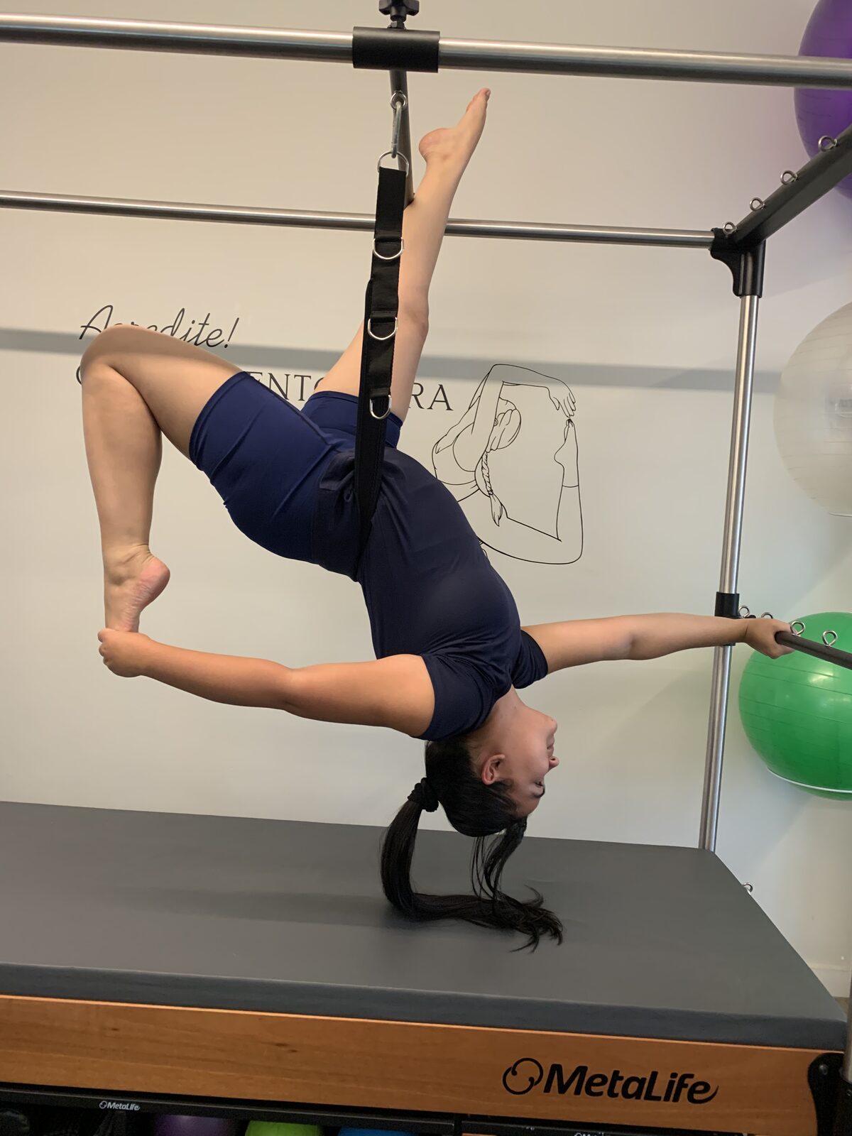 Aluna em invertida com alças no Cadillac de pilates
