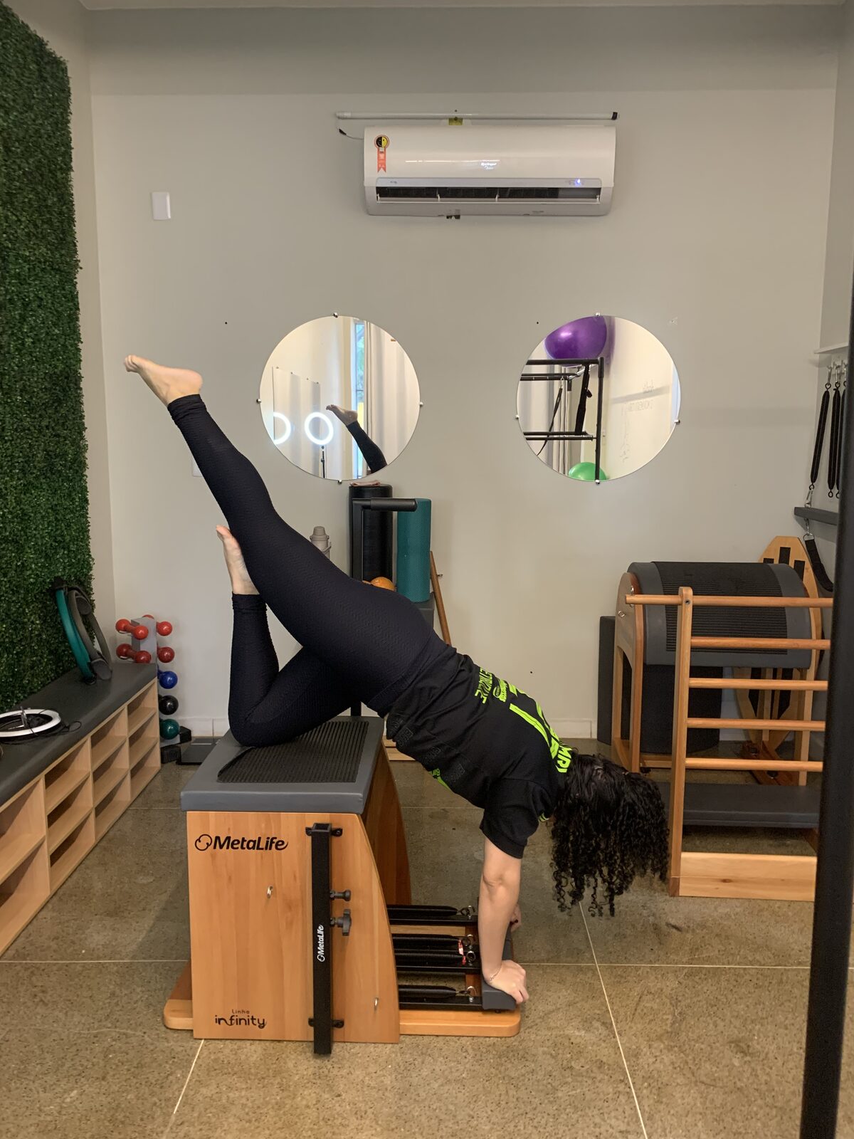 Aluna em parada de mãos invertida na cadeira de pilates